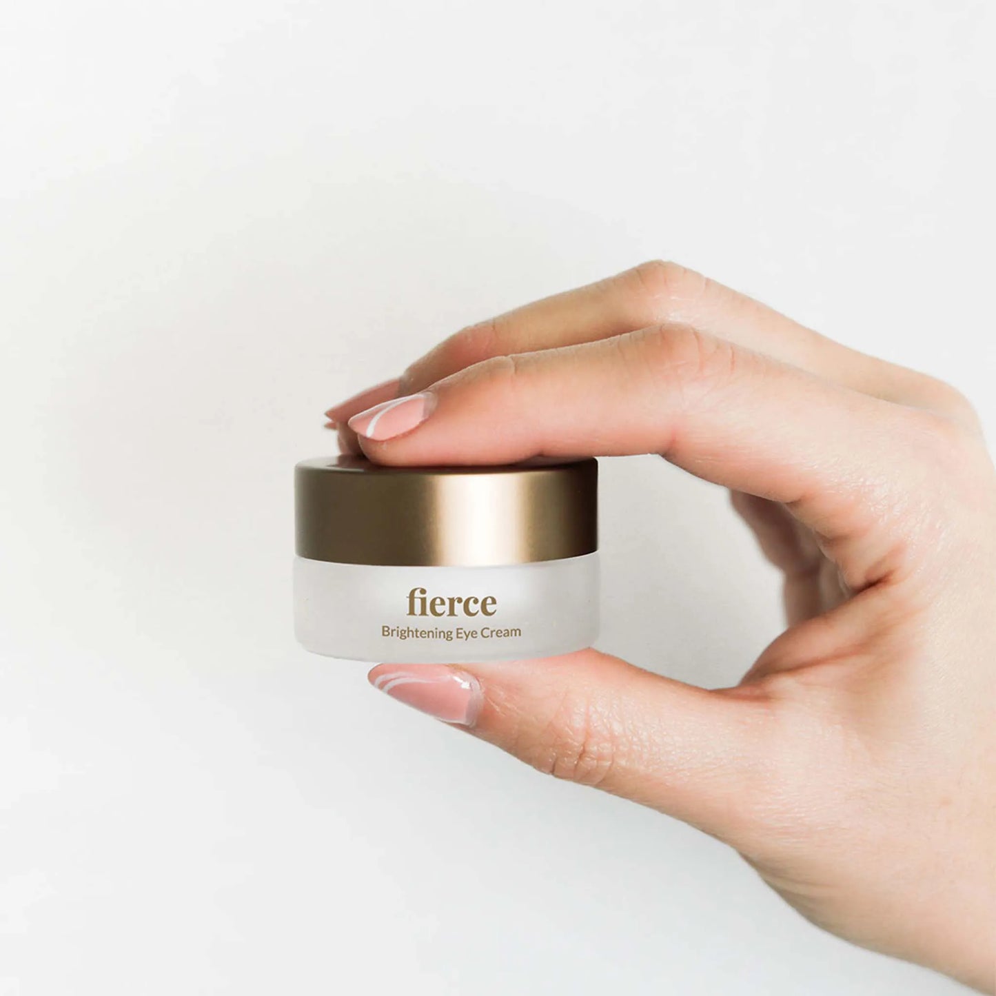 Een vrouwenhand houdt de doos Nordic Cosmetics Oogcrème vast.