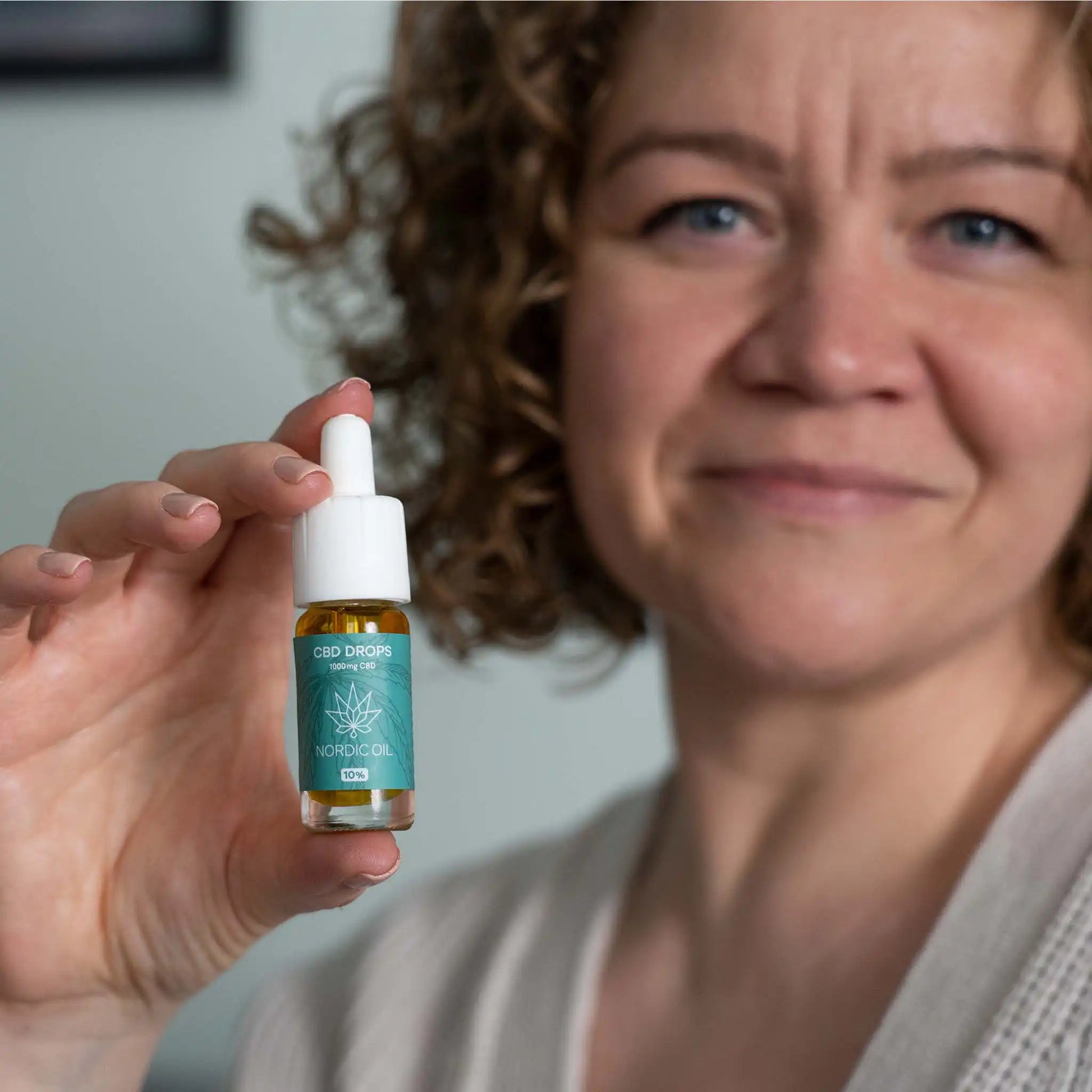 een vrouw houdt de CBD olie in de camera.