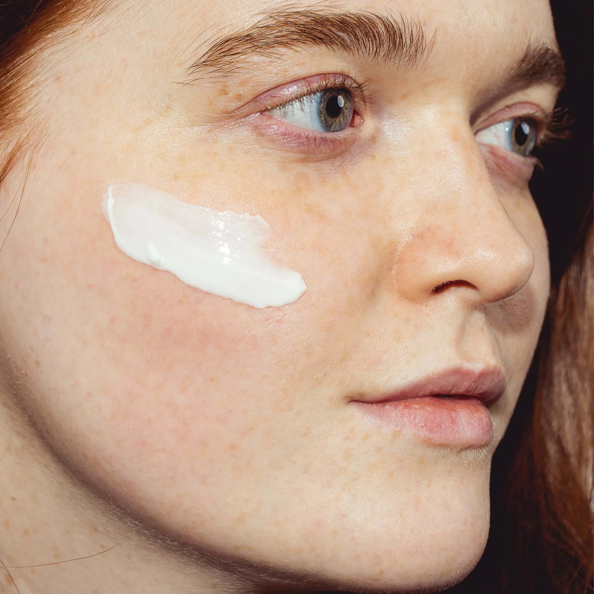 een vrouw smeerde de crème op haar wang