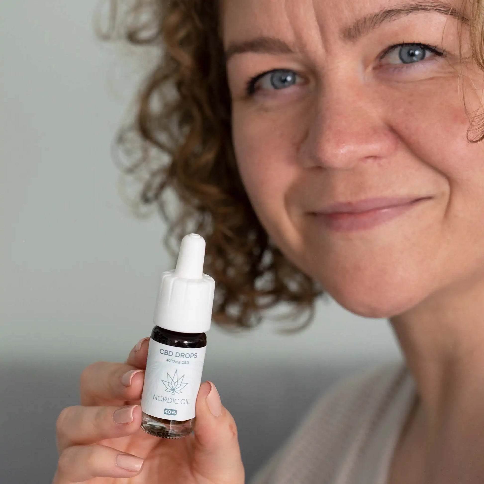 een vrouw houdt de CBD olie in de camera